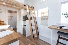 a room with a bed, desk and ladder in it