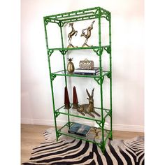 a green metal shelving unit with deer figurines on top and zebra rug