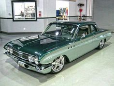 a green car parked in a garage next to a wall with pictures hanging on it