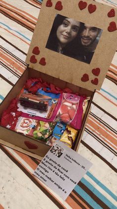 an open cardboard box filled with valentine's day treats and candies on top of a striped tablecloth