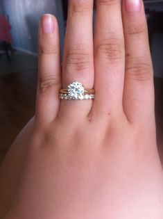 a woman's hand with a diamond ring on top of her left hand,