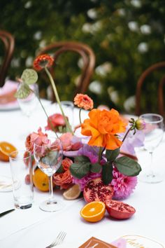 the table is set with oranges and pink flowers