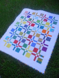 a quilt on the ground with grass in the background