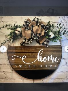 a wooden sign that says home sweethome hanging on a brick wall with greenery