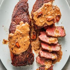 a white plate topped with steak covered in gravy and sauce on top of it