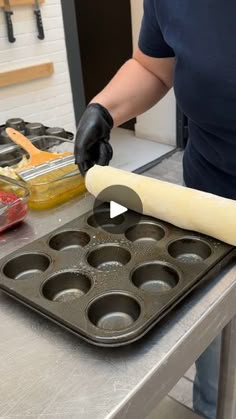 a person in a kitchen preparing food with a rolling dough on top of a muffin pan