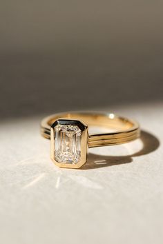 a diamond ring sitting on top of a white surface with sunlight coming through the window