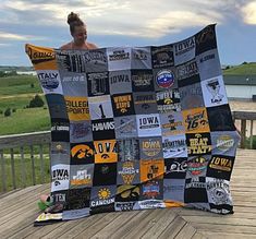 a woman is holding up a quilt made from old t - shirts on a deck