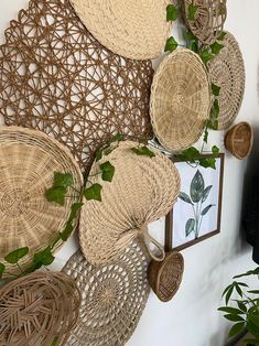 wicker baskets are hanging on the wall next to a mirror and potted plant