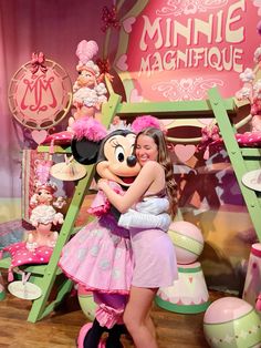 a girl hugging minnie mouse in front of some decorations