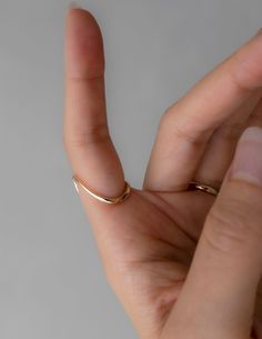 a woman's hand with a gold ring on her thumb and the middle finger