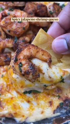 a person is holding up a piece of shrimp and tortilla chips to eat