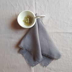 a white bowl filled with food next to a gray napkin on top of a table