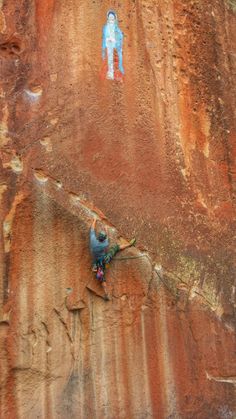 a man climbing up the side of a cliff next to a blue and white figure