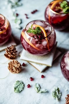 two glasses filled with fruit and garnish on top of a white tablecloth