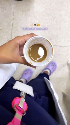 a person is holding a cup of coffee in their hand while sitting on the floor