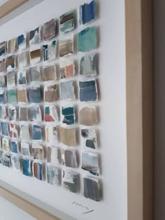 a white wall with many different colored tiles on it and a wooden frame around the edges