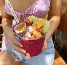 a woman is holding a fruit smoothie in her hands