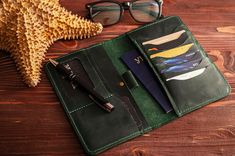 an open wallet sitting on top of a wooden table next to a pair of glasses