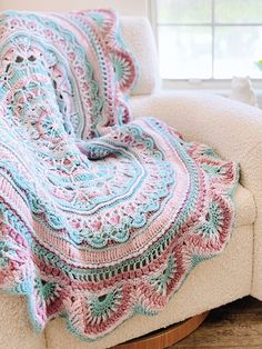 a crocheted blanket sitting on top of a couch next to a potted plant