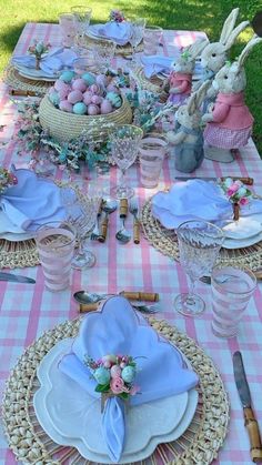 the table is set with pink and white plates, napkins, silverware, and bunny ears