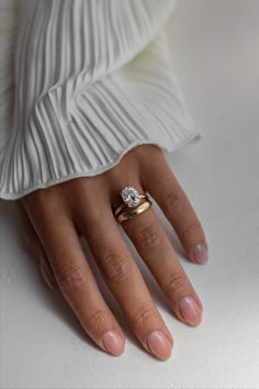 a woman's hand with a diamond ring on top of her finger and white dress