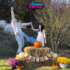 a man and woman standing on top of a hay bale