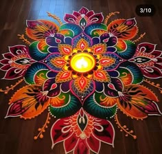 a candle is lit in the center of an intricately designed rang art design on a wooden floor