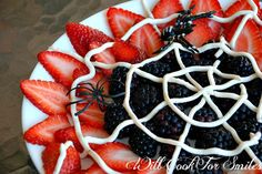 a white plate topped with strawberries and blackberries on top of a spider web