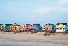 a row of colorful houses sitting on top of a sandy beach