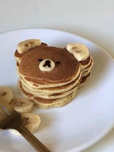 a stack of pancakes topped with bananas and a teddy bear face