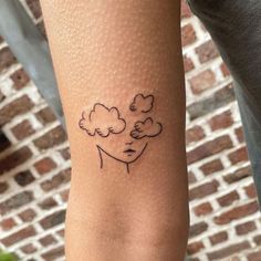 a person with a tattoo on their arm that has clouds in the shape of a woman's head