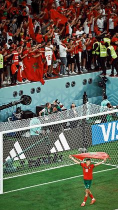a man standing on top of a soccer field holding a red frisbee in front of a crowd