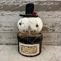 two white pumpkins sitting on top of each other in a black hat and tin can