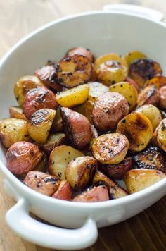 a white bowl filled with cooked potatoes on top of a wooden table