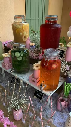 several jars filled with different types of drinks on top of a table covered in flowers