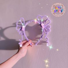 a hand holding a purple stringed heart shaped object with lights on the side and stars in the background