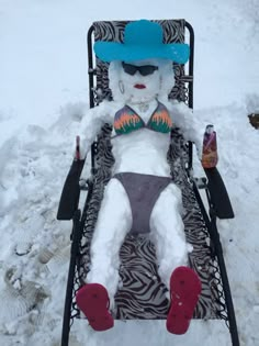 a teddy bear sitting in a lawn chair covered in snow with a hat and sunglasses on