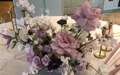 a vase filled with lots of flowers on top of a white tablecloth covered table