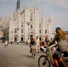 people are riding bicycles in front of a cathedral