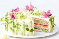 a white plate topped with a cut in half cake covered in cucumber and radishes