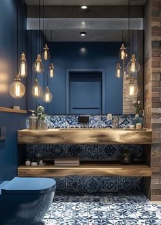 a bathroom with blue walls and tile flooring, lights hanging from the ceiling over the sink