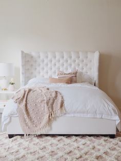 a white bed sitting in a bedroom on top of a carpeted floor next to a window