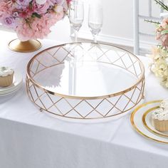 a table topped with cupcakes and flowers on top of a white table cloth