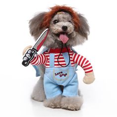 a small dog dressed in overalls and holding a pair of scissors with its tongue out