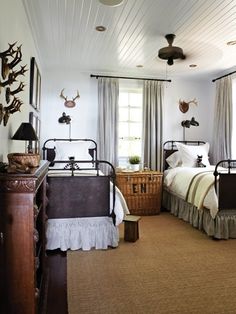 two twin beds in a bedroom with antlers on the wall and curtains over them