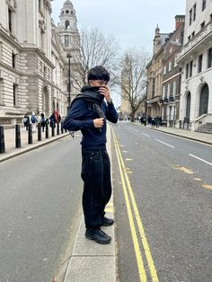 a man standing on the side of a street talking on a cell phone