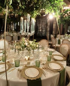 the table is set with white plates and green napkins, silverware and candles