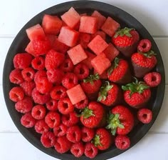 a bowl filled with watermelon, raspberries and strawberries on top of a table