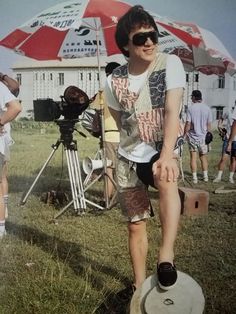 a man standing in the grass with an umbrella behind him